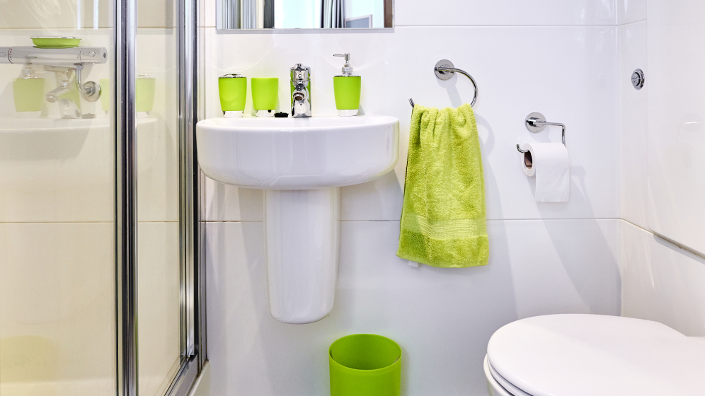 A small bathroom with a sink, toilet and partial view of a shower cubicle